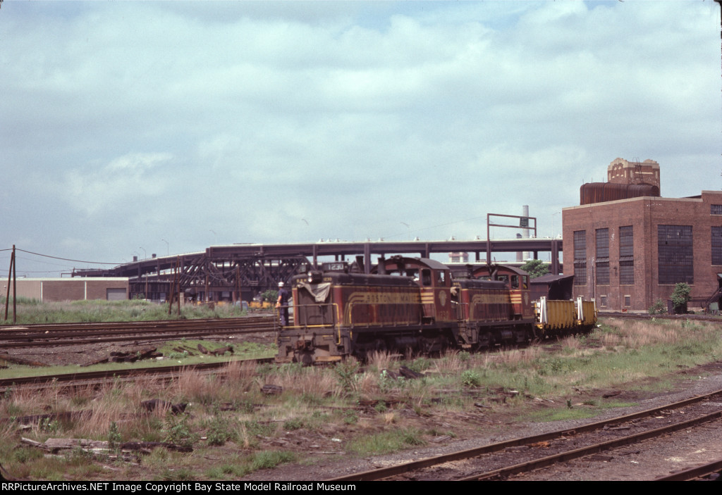 BM 1230 & BM 802 haul welded rail for the MBTA Green Line 'D' Branch past Boston Engine Terminal